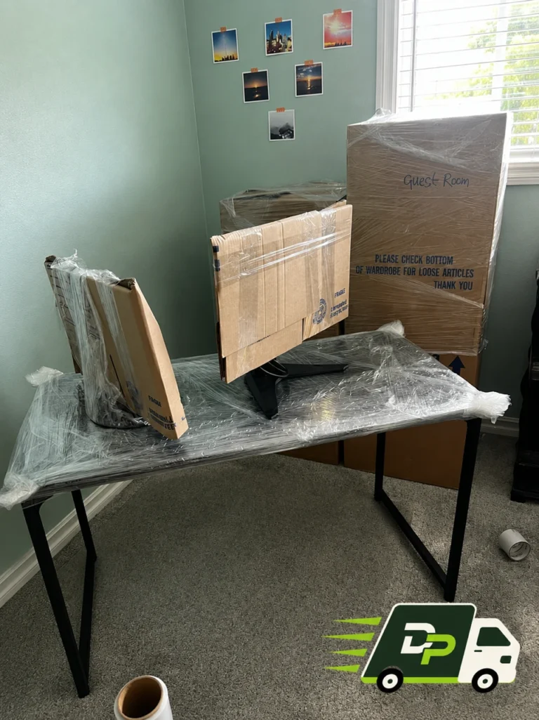 Professional movers carefully wrapping furniture and electronics at a home by Dana Point Moving Company